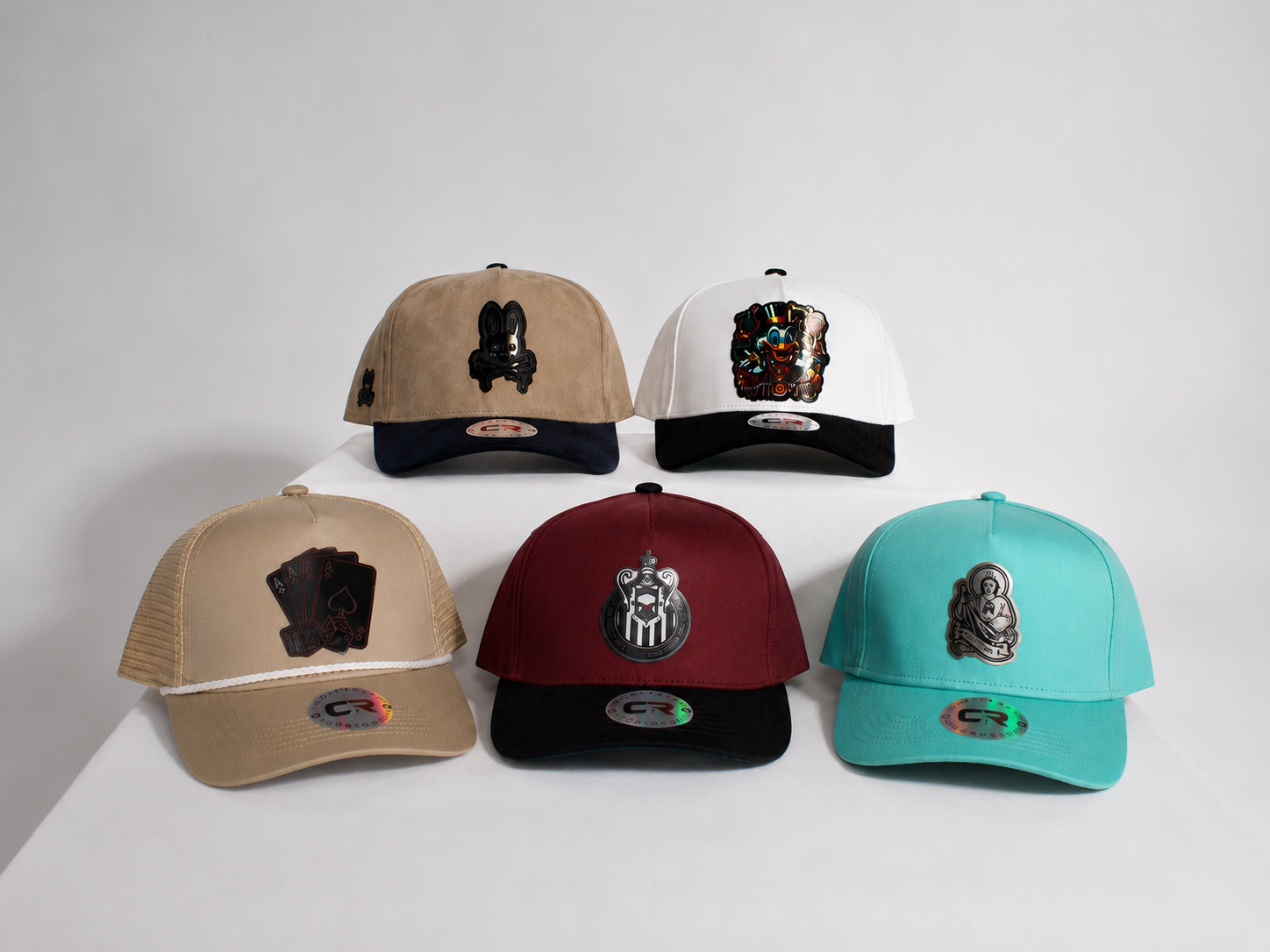 Five custom hats arranged on a white display